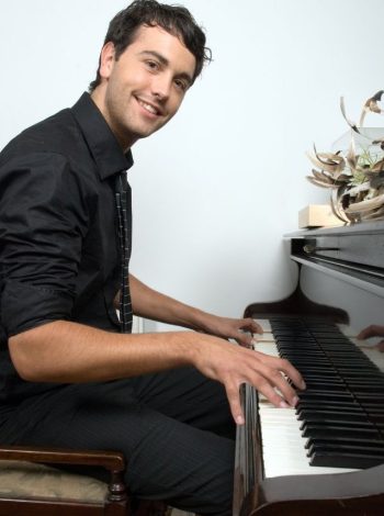 un homme souriant qui joue du piano